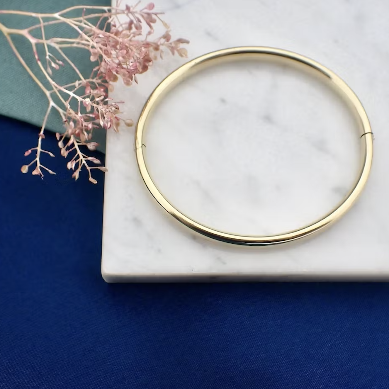 Geelgouden slavenarmband op een marmeren ondergrond